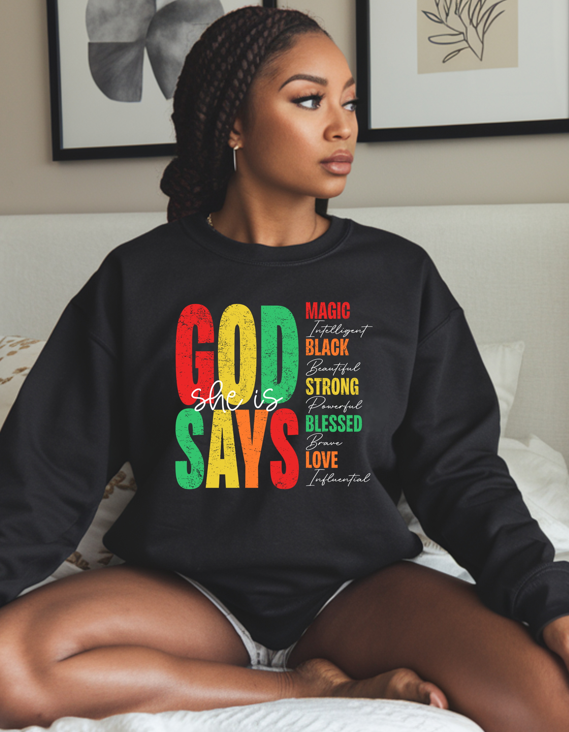 Woman wearing a black sweatshirt with colorful text sitting on a couch.
